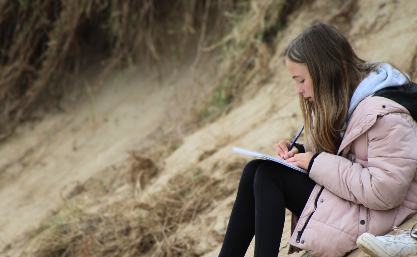 A student writing on the beach
